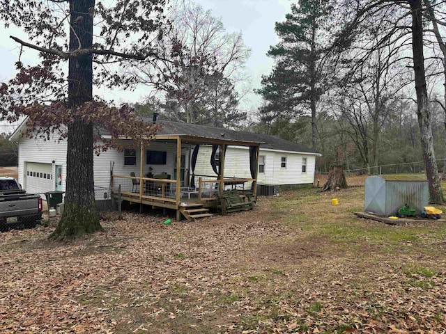 rear view of property featuring central AC, a deck, and a garage