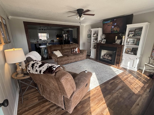 living room with ceiling fan, a textured ceiling, dark hardwood / wood-style floors, and ornamental molding