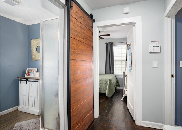  - corridor featuring dark wood finished floors, baseboards, and a barn door