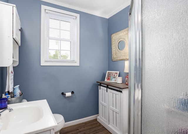  - bathroom with wood finished floors, baseboards, toilet, vanity, and crown molding