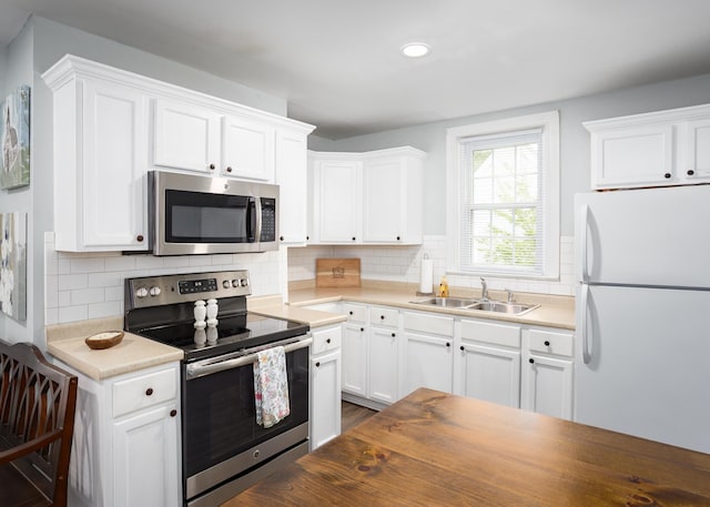  - kitchen featuring stainless steel appliances, a sink, white cabinets, backsplash, and recessed lighting