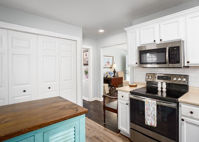 - kitchen with stainless steel appliances, butcher block countertops, light wood-style flooring, white cabinetry, and recessed lighting