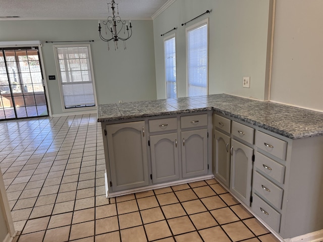 kitchen featuring a peninsula, ornamental molding, light tile patterned flooring, and decorative light fixtures