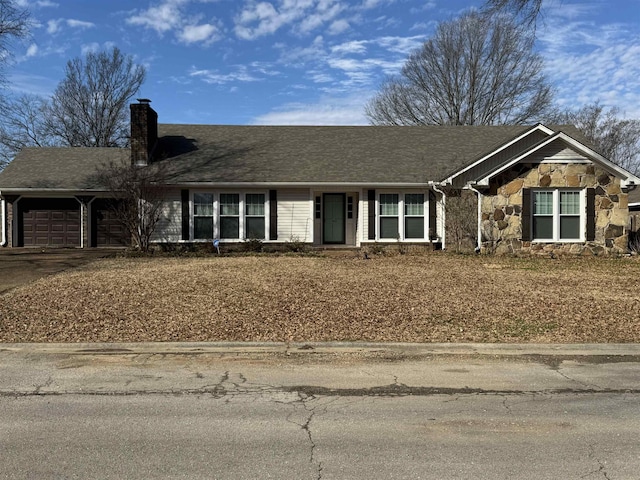 single story home with an attached garage, stone siding, driveway, roof with shingles, and a chimney