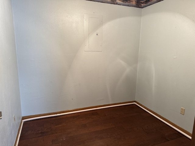 unfurnished room with electric panel, baseboards, and wood finished floors