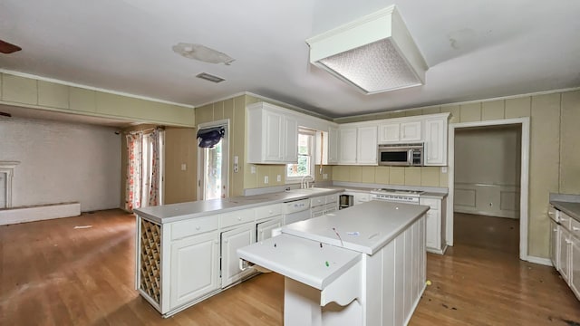  - kitchen with stainless steel microwave, dishwasher, light wood-style flooring, ornamental molding, and a center island