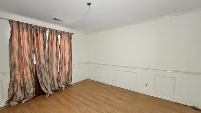 - unfurnished room featuring light wood finished floors, a wainscoted wall, ornamental molding, and a decorative wall