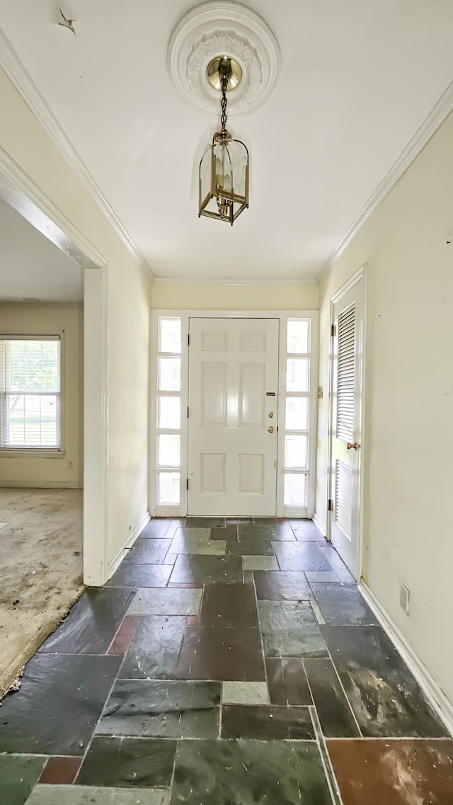  - entrance foyer with healthy amount of natural light, ornamental molding, stone tile floors, and a chandelier