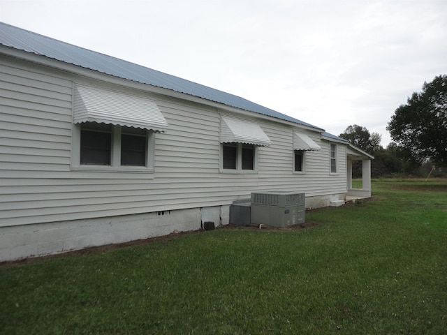 view of side of home with central AC and a lawn