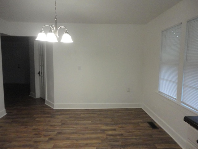 unfurnished dining area featuring a chandelier and dark wood-type flooring