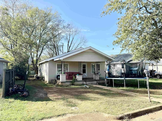 bungalow-style home featuring ac unit, a porch, a trampoline, and a front lawn