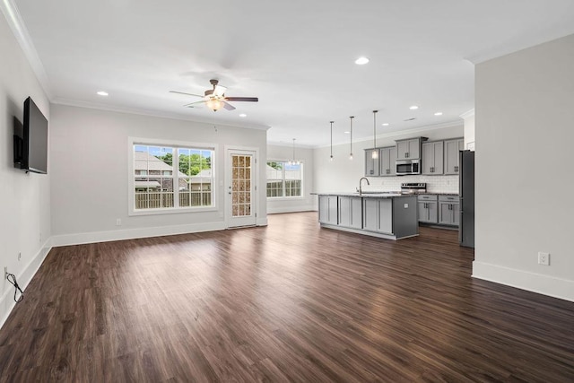 unfurnished living room with dark hardwood / wood-style flooring, sink, ornamental molding, and ceiling fan