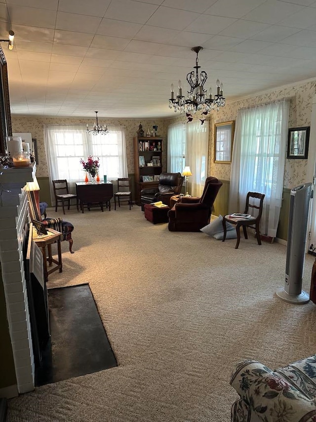 carpeted living room with a fireplace and a chandelier