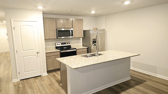 kitchen with sink, light stone countertops, an island with sink, and appliances with stainless steel finishes