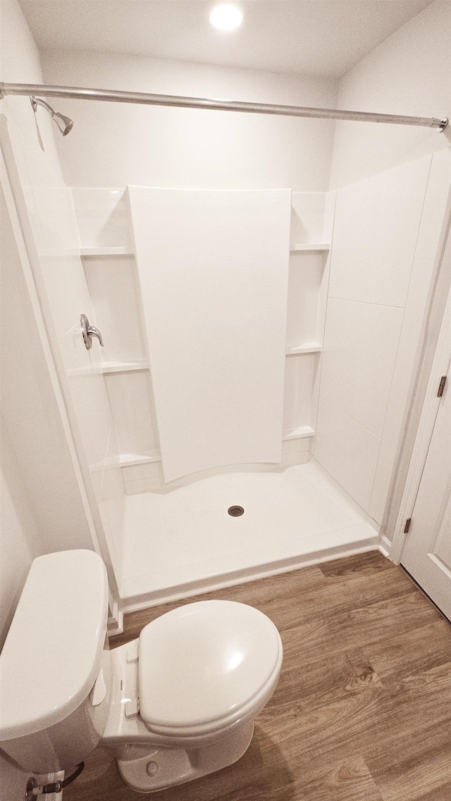 bathroom with hardwood / wood-style flooring, toilet, and a shower