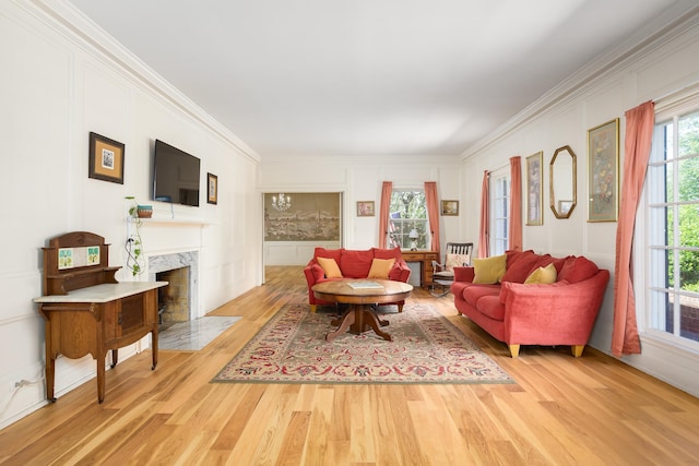  - living room with a premium fireplace, ornamental molding, a decorative wall, and light wood-style flooring