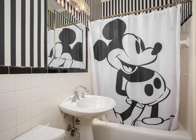  - bathroom featuring tile walls and shower / tub combo
