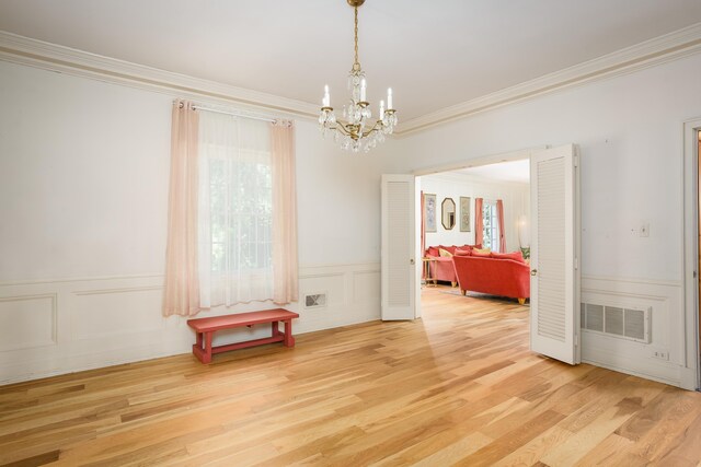  - dining room featuring a wainscoted wall, visible vents, light wood-style floors, crown molding, and a chandelier