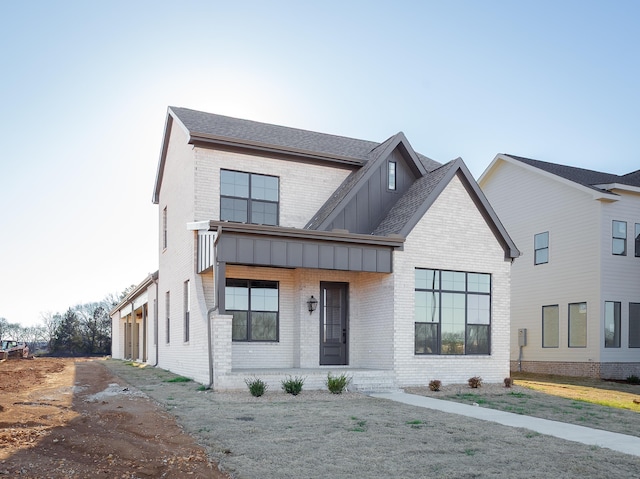 modern inspired farmhouse featuring board and batten siding, brick siding, and a shingled roof