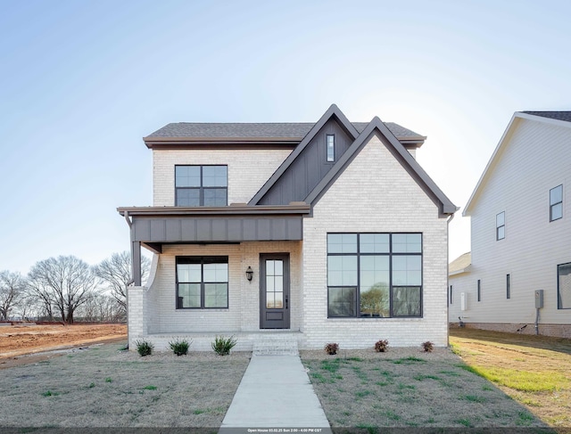 modern farmhouse with a front lawn, board and batten siding, and brick siding