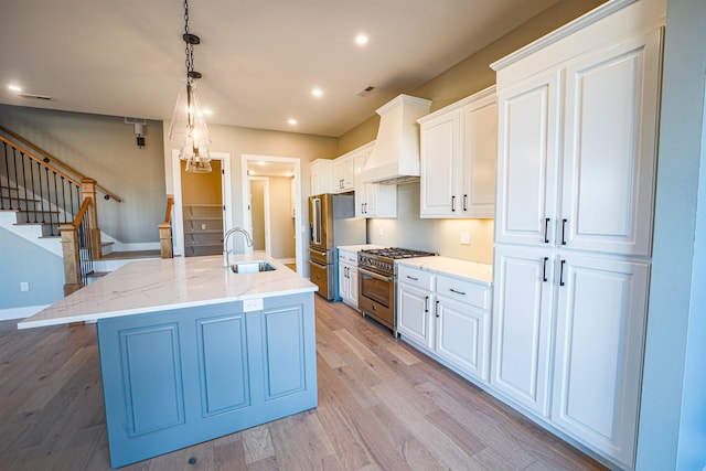 kitchen featuring appliances with stainless steel finishes, an island with sink, white cabinetry, and custom exhaust hood