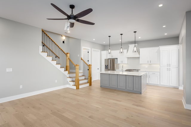 kitchen with light wood finished floors, stainless steel fridge, white cabinets, light countertops, and recessed lighting