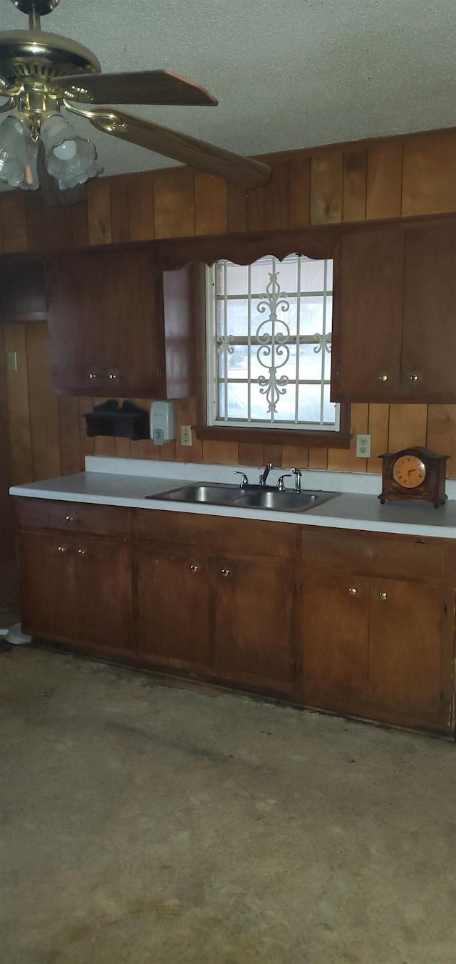 kitchen with lofted ceiling, sink, ceiling fan, a textured ceiling, and wood walls