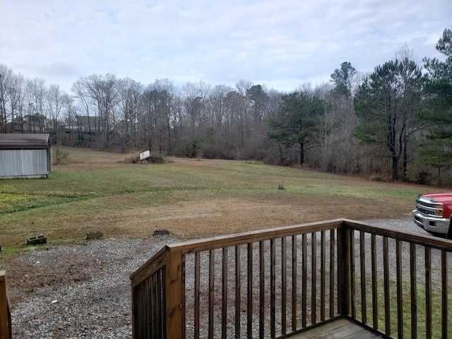 wooden deck featuring a shed and a lawn