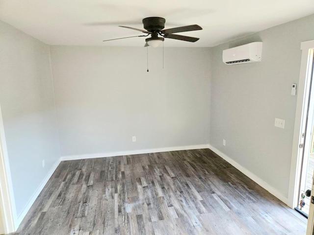 spare room featuring a wall unit AC, a ceiling fan, baseboards, and dark wood-style flooring