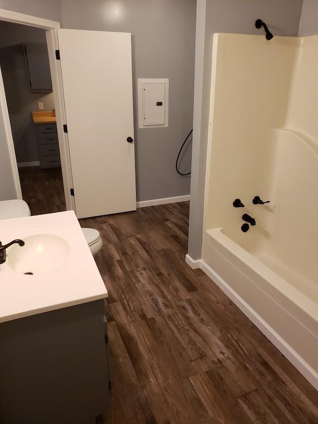 bathroom featuring electric panel, toilet, wood finished floors, bathtub / shower combination, and vanity