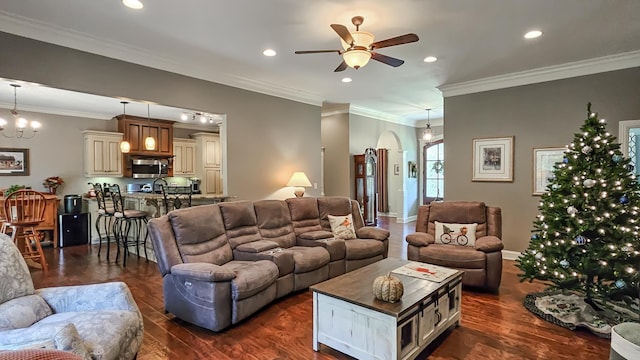 living room with dark hardwood / wood-style flooring, ceiling fan with notable chandelier, and ornamental molding