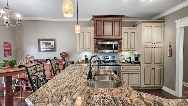 kitchen with pendant lighting, sink, light stone countertops, cream cabinetry, and stainless steel appliances