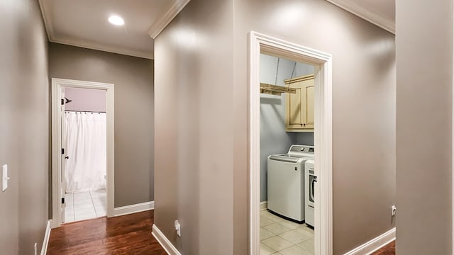 corridor with washing machine and clothes dryer, light tile patterned floors, and ornamental molding