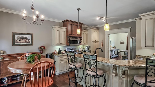 kitchen featuring cream cabinets, hanging light fixtures, light stone counters, a notable chandelier, and a kitchen bar