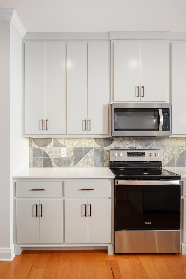 kitchen with tasteful backsplash, appliances with stainless steel finishes, and white cabinetry