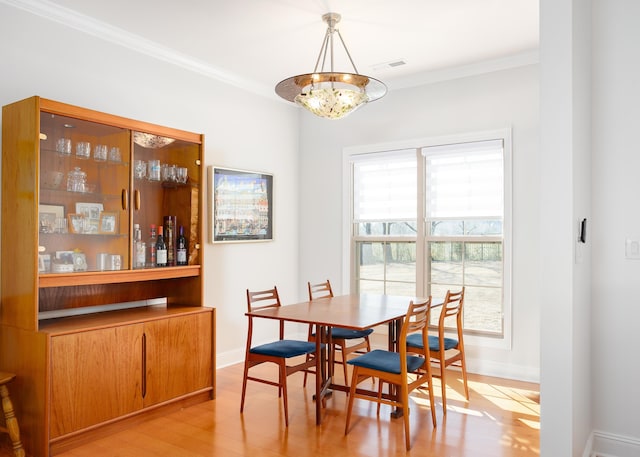 dining area featuring visible vents, light wood-style floors, a chandelier, and crown molding