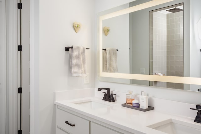 bathroom featuring a sink, a shower, and double vanity