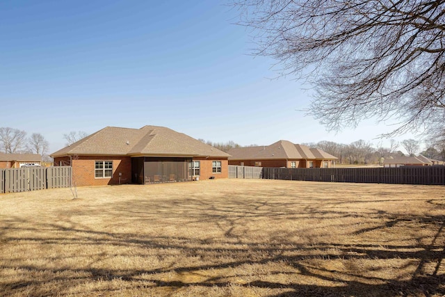 back of property featuring a fenced backyard, brick siding, and a lawn