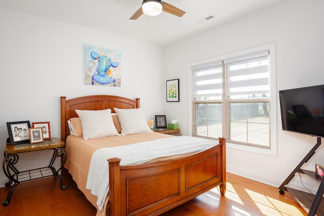 bedroom with ceiling fan, light wood-style floors, visible vents, and baseboards