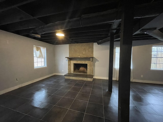 basement featuring a wealth of natural light, a high end fireplace, and dark tile patterned floors