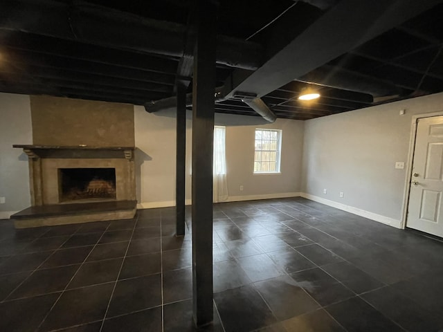 basement with dark tile patterned floors and a fireplace