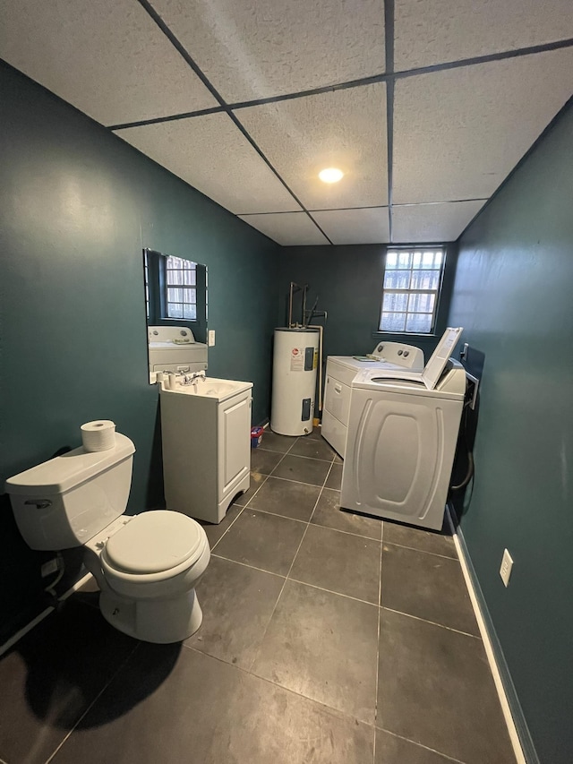 bathroom featuring tile patterned flooring, toilet, electric water heater, a drop ceiling, and washer and clothes dryer