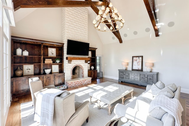  - living area with high vaulted ceiling, a chandelier, wood finished floors, a brick fireplace, and beamed ceiling