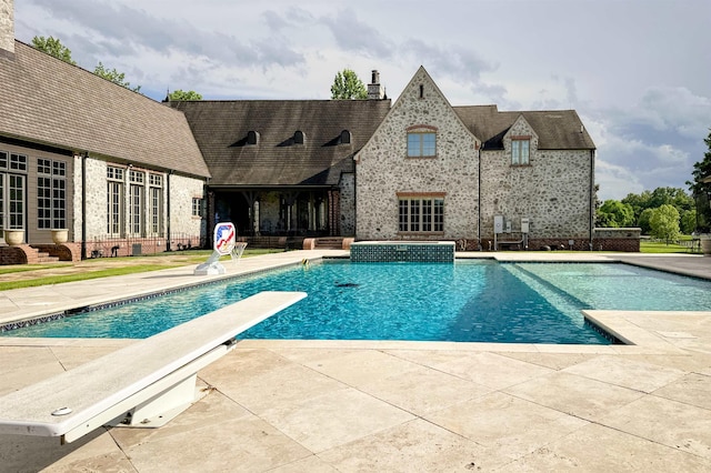  - outdoor pool with a diving board and a patio area