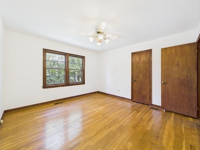  - unfurnished bedroom with two closets, light wood-style flooring, and a ceiling fan