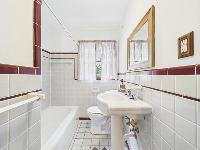  - bathroom with tile walls, tile patterned flooring, and a tub