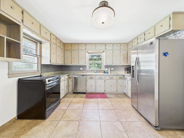  - kitchen featuring appliances with stainless steel finishes, light countertops, backsplash, and light tile patterned floors