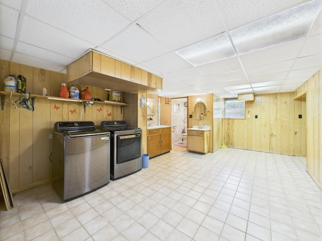 - kitchen with wooden walls, a paneled ceiling, independent washer and dryer, open shelves, and light flooring