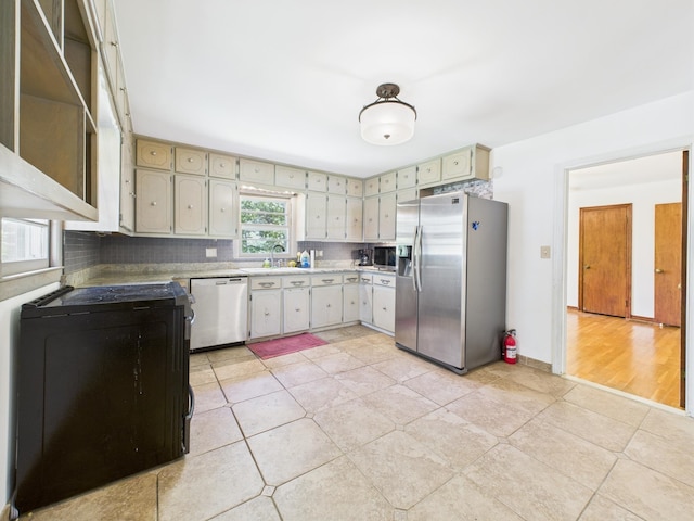  - kitchen with stainless steel appliances, light countertops, light tile patterned floors, and decorative backsplash