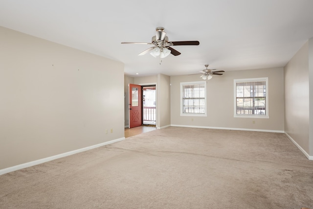 spare room with a ceiling fan, light carpet, and baseboards